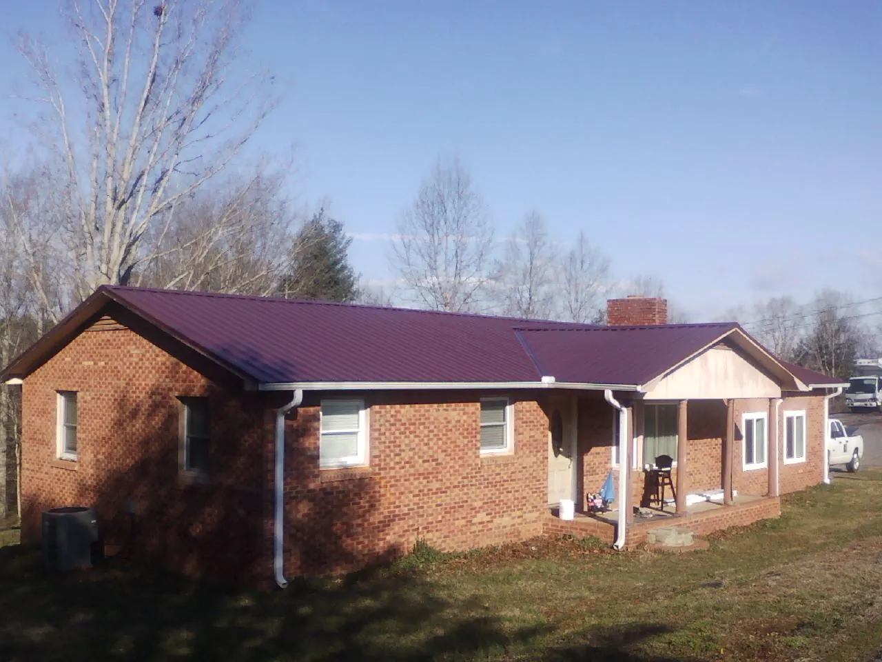 Burgundy metal roof on a brick ranch home with a new addition in Pena Blanca