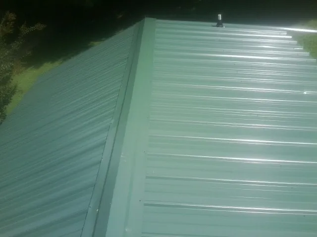 New green metal panels meeting at the ridge of a roof — Flat Roof Repair work by our crew in Pena Blanca