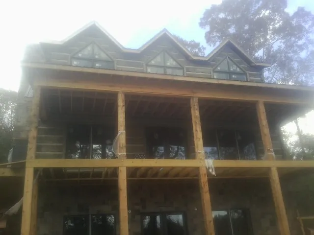 Dormers and porch framing on a large log home under construction — Roof Coating work by our crew in Pena Blanca