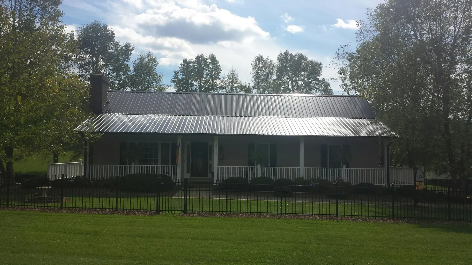Gray metal roof on a brick ranch with a full width front porch — Gutter Guard Installation work by our crew in Pena Blanca