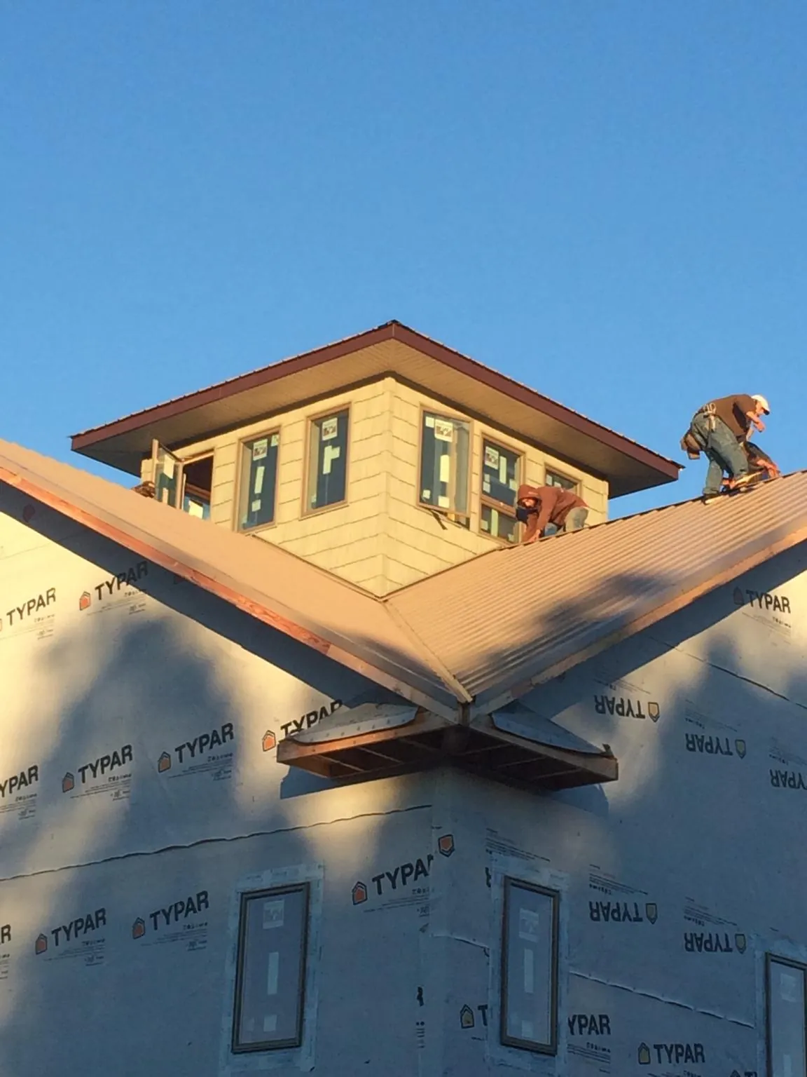 Roofers working around a rooftop cupola on a new metal roof at sunset — Roof Waterproofing in Pena Blanca by Roofing Brothers